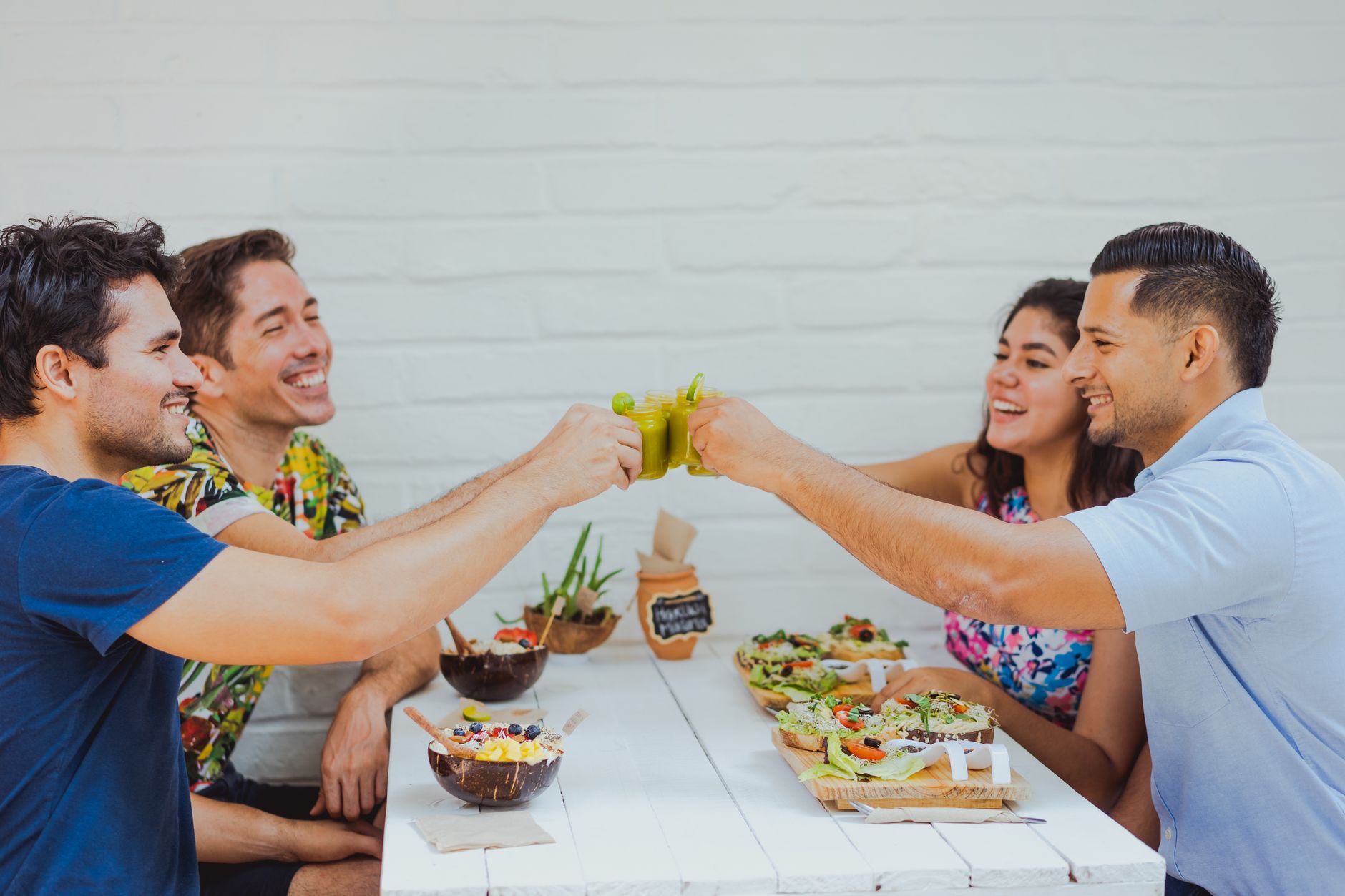 Friends laughing together over a healthy lunch of smoothie bowls and toast